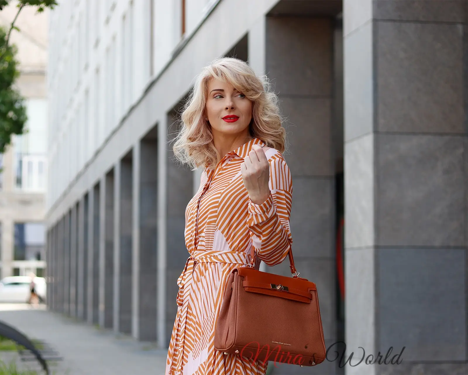 Woman in striped dress with handbag outdoors.